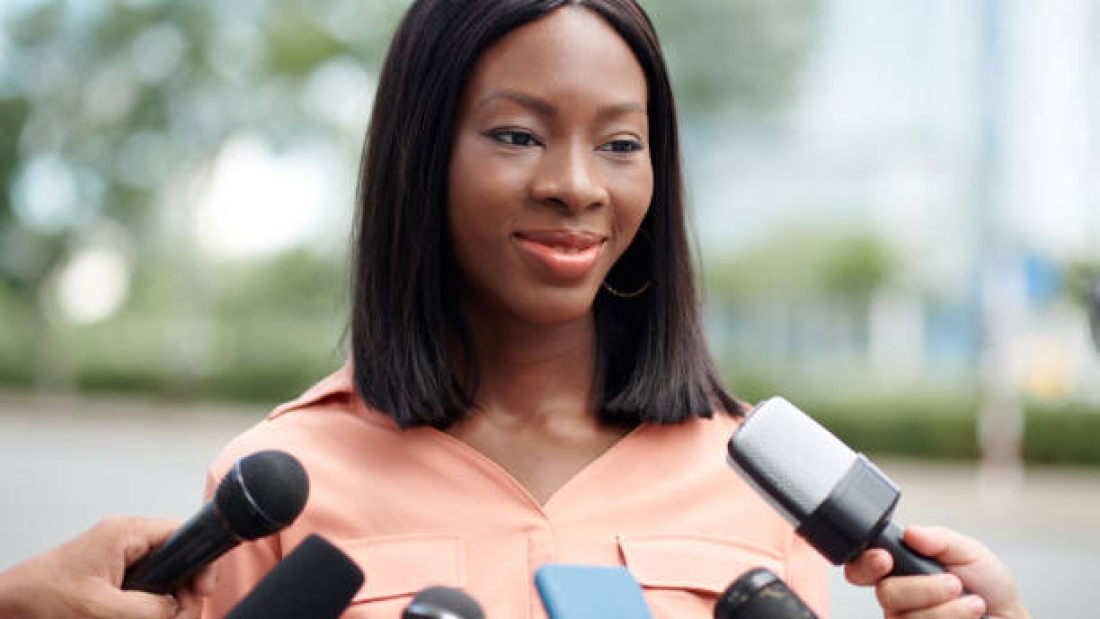 Portrait of cheerful company representative answering questions on journalists