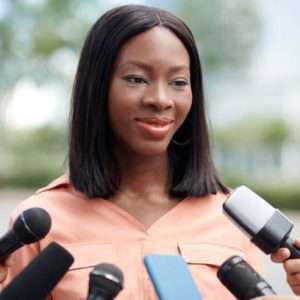 Portrait of cheerful company representative answering questions on journalists